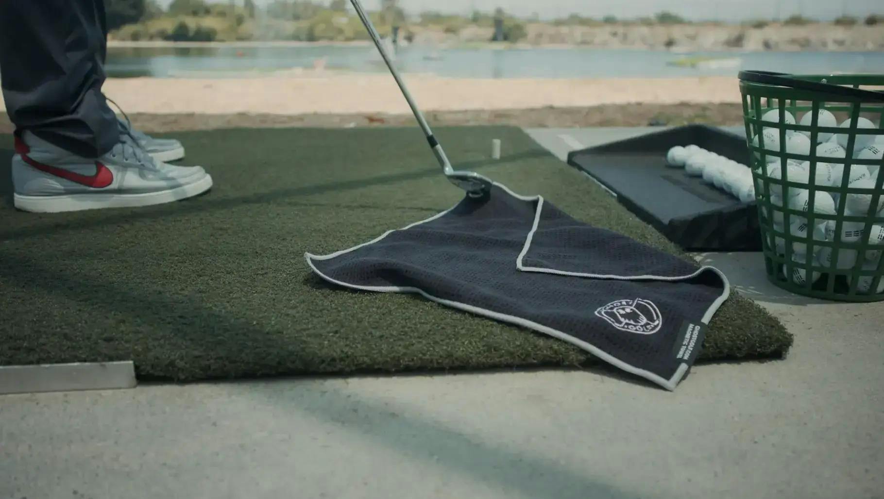 A Ghost Golf towel on the floor of a driving range 